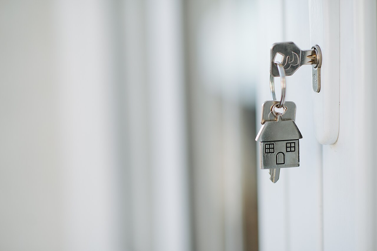 Clé avec porte-clés en forme de maison engagée dans une serrure
